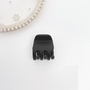 Close-up of matte black small hair claw clip with sturdy multi-tooth design on white