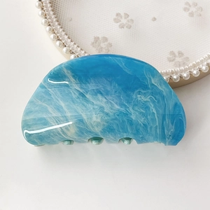 Close-up of blue marble acetate hair claw clip with smooth edges on lace background