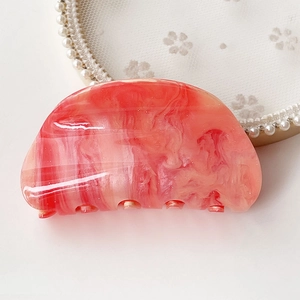 Detailed close-up of marble texture hair claw clip with elegant pink gradient finish