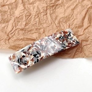 Detail of elegant acetate hair clip with marble pattern on a textured paper background