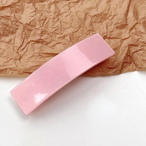Elegant pink acetate hair clip with a smooth glossy finish and curved rectangular design