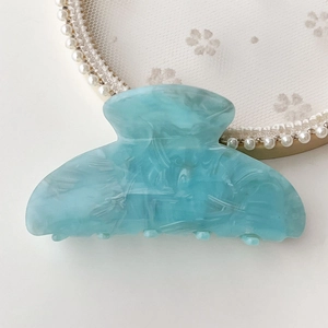 Close-up of light blue marble textured acetate hair claw clip for elegant bun styling