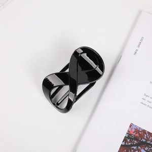 Detailed top view of a glossy black infinity-shaped hair claw clip on a white background