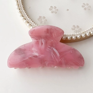 Close-up of pink marble pattern acetate hair claw on a white lace and pearl tray