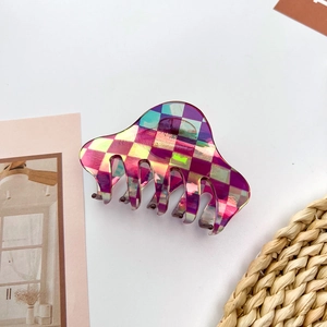 Detail of a geometric acetate hair claw featuring a holographic checkered pattern