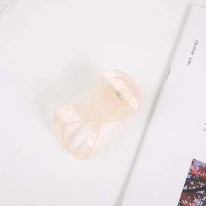 Close-up of peach hair claw clip with white polka dots and elegant infinity cross design