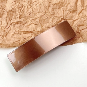 Polished bronze acetate rectangular hair clip showing sleek metallic mirror finish details