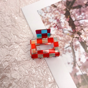 Detail of red and blue checkered acetate hair claw clip with a hollow rectangular design