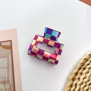 Macro detail of a colorful checkered acetate hair claw clip with iridescent finish