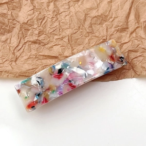 Detail of a rectangular acetate hair clip with colorful marble stone pattern on paper