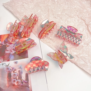 Detailed view of pink checkerboard hair claws with holographic finish and gradient effect
