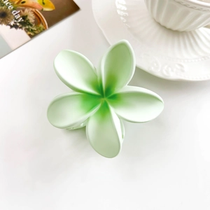 Detail of light green matte plumeria flower hair claw clip with gradient texture