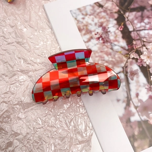 Close-up of red and iridescent checkerboard claw clip with smooth glossy finish