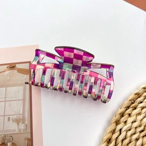 Detailed view of large checkered hair claw clip with purple and green acetate finish