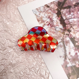 Macro view showing the glossy red and yellow checkered acetate hair claw clip details