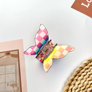 Macro detail of butterfly hair claw clip with gradient checkered pattern and metal spring
