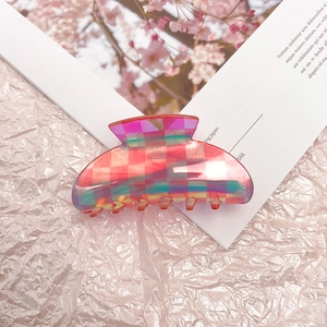 Pink checkered acetate hair claw clip with iridescent finish on textured fabric
