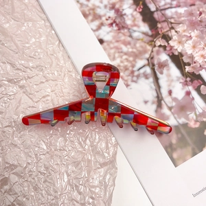Detail of red and blue checkered hair claw clip with iridescent finish and metal spring