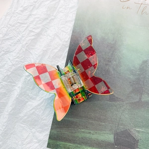 Detailed shot of red checkerboard butterfly claw clip with iridescent laser finish