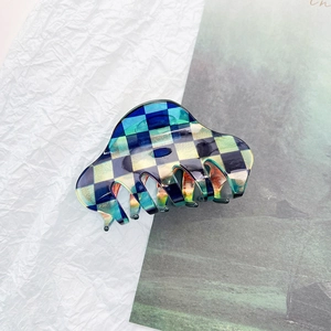 Detailed close-up of a checkered acetate hair claw clip with colorful iridescent finish