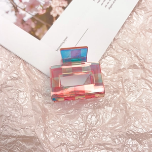 Detailed view of iridescent checkered claw clip with pink and green gradient patterns