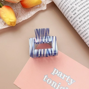 Détail de la pince à cheveux en acétate marbré bleu sur carte rose avec fleurs