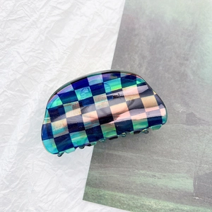 Detailed macro shot of a geometric checkered hair claw clip with colorful iridescent finish