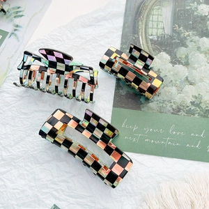 Detailed view of checkered hair claws with iridescent laser finish in black acetate
