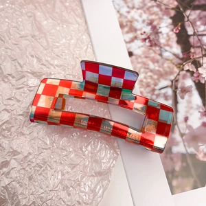 Detail of red and white checkered hair claw clip with holographic laser finish and spring