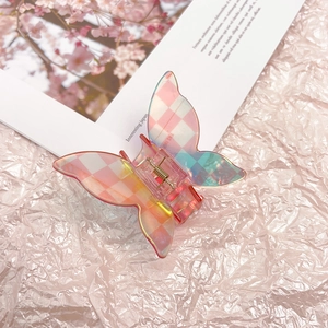 Macro detail of butterfly hair claw with pink checkered pattern and iridescent finish