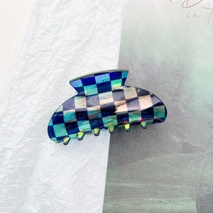 Detailed macro view of the checkerboard hair claw clip with emerald green and blue finish
