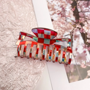 Detailed close-up of a red and blue checkered acetate hair claw clip with a glossy finish