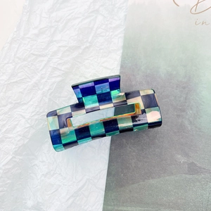 Detail of laser texture checkerboard hair claw clip in blue and green glossy finish