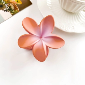 Detailed macro view of matte orange-pink gradient plumeria hair claw on a white background