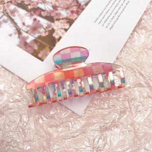 Detailed view of a pink checkered acetate hair claw clip with iridescent finish