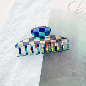 Close-up of a large checkered hair claw clip with colorful laser-finish acetate squares