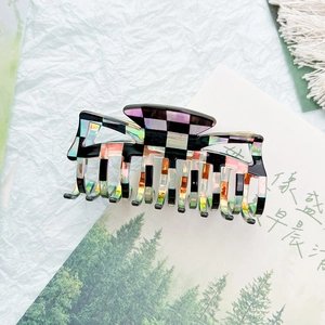 Macro shot of large black and white checkerboard hair claw clip with iridescent finish