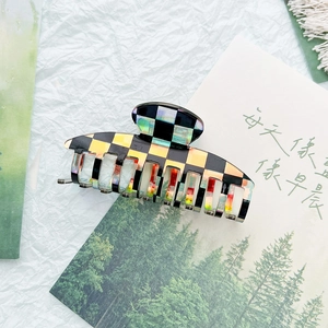 Detail of checkered acetate hair claw clip with holographic finish and metal spring