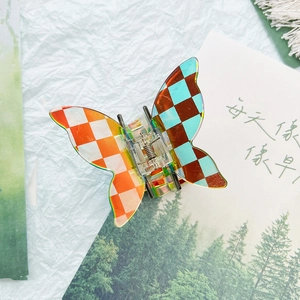 Detail of butterfly-shaped checkered hair claw clip with colorful acrylic finish