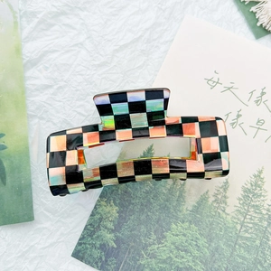 Detail of holographic checkerboard hair claw clip with glossy laser finish on white background