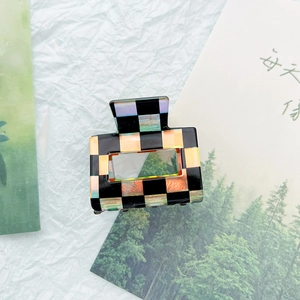 Detail of checkered hair claw clip with laser texture on decorative background