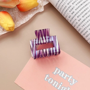 Détail d'une pince à cheveux en acétate à rayures violettes avec une finition brillante