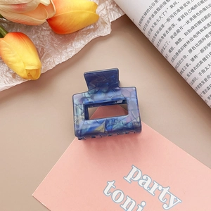 Détail d'une pince à cheveux en acétate marbré bleu avec tulipes sur carte rose