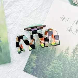 Macro detail of the checkered hair claw clip with colorful wave pattern and metal spring