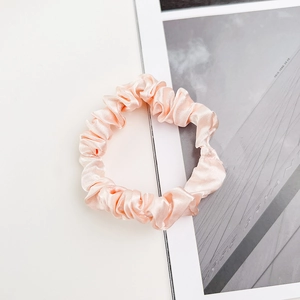 Gros plan d'un chouchou en satin rose montrant la texture brillante et plissée