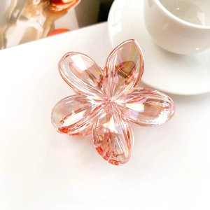 Close-up of peach pink flower hair claw with iridescent finish on white table