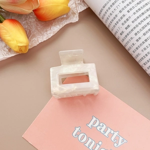 Détail d'une pince à cheveux carrée en acétate marbré crème avec décor floral