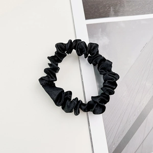 Vue détaillée du chouchou en satin noir montrant la texture plissée brillante et le tissu doux