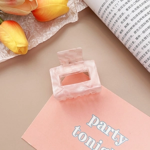 Gros plan sur la pince à cheveux carrée évidée en acétate rose marbré avec tulipes