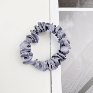 Détail du tissu en satin gris doux et des plis fins de ce chouchou à l'aspect soyeux